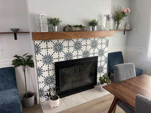 Room details with a wainscoted wall, a tile fireplace, and wood finished floors