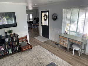 Entryway with crown molding, visible vents, wainscoting, and wood finished floors