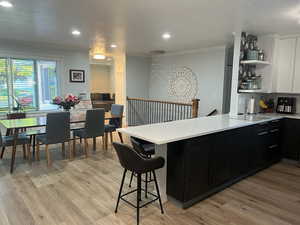 Kitchen with crown molding, open shelves, light countertops, a peninsula, and white cabinetry