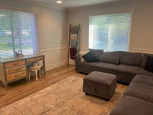 Living room featuring wainscoting, recessed lighting, ornamental molding, and light wood-type flooring
