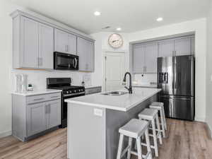 Sleek black stainless steel appliances, plus the matching refrigerator is included.  Quartz counters and classic grey shacker style cabinets.