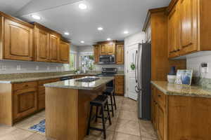 Staggered depth cabinets, granite countertops and a center island with built-in breakfast bar