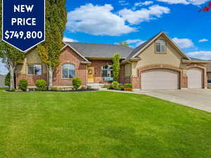 View of front of property featuring a front lawn, concrete driveway, a garage, and stucco siding