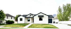 Modern farmhouse featuring fence, an attached garage, driveway, and a front yard