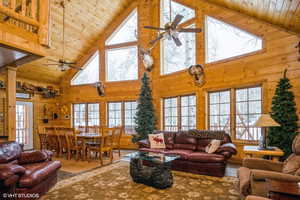 Living room with ceiling fan, wooden ceiling, a wealth of natural light, and high vaulted ceiling