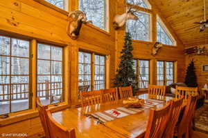 Dining space with wooden walls, high vaulted ceiling, and a healthy amount of sunlight