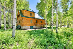 Back of house with metal roof and log siding