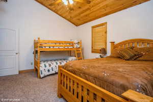 Bedroom featuring wood ceiling, a ceiling fan, vaulted ceiling, baseboards, and carpet floors