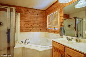 Bathroom with vanity, wood walls, a shower stall, and a tub with jets