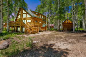 Rear view of house with stairs, a deck, an outdoor structure, and log exterior