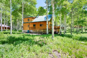 Back of property with a wooden deck, metal roof, and view of wooded area