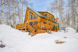 Snow covered rear of property with a deck