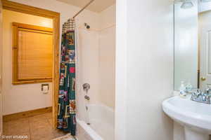 Full bath with baseboards, a sink, tile patterned floors, and shower / bath combination with curtain