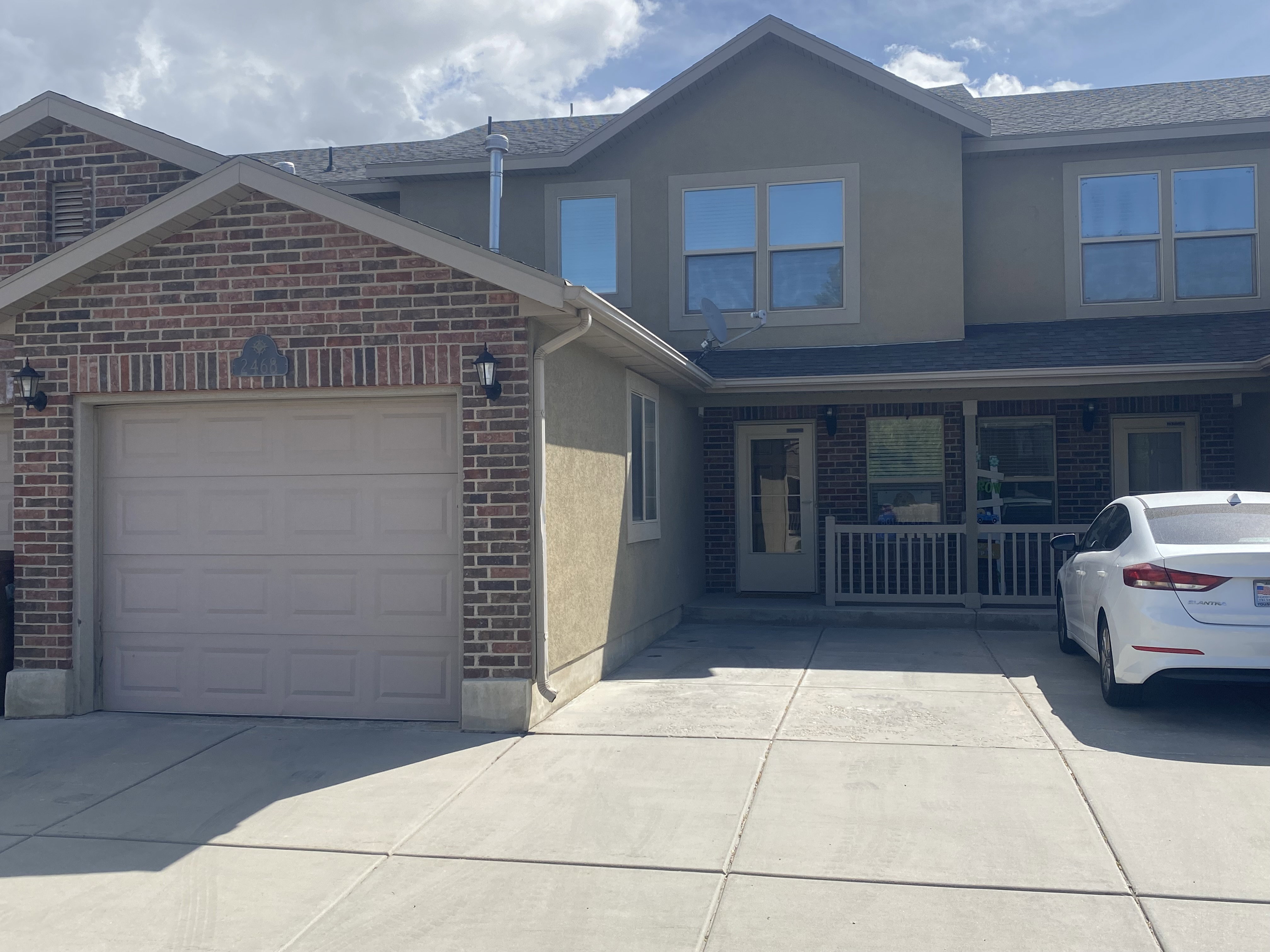Traditional-style home with brick siding, a garage, stucco siding, a porch, and driveway