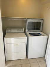 Laundry room with independent washer and dryer, light tile patterned flooring, and laundry area