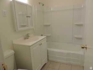 Bathroom with vanity, tile patterned flooring, bathtub / shower combination, and toilet