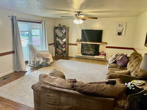 Living area featuring visible vents, wood finished floors, baseboards, ceiling fan, and a textured ceiling