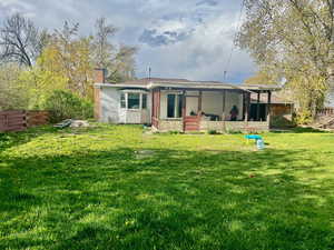 Back of property featuring fence, a lawn, a chimney, and a sunroom