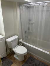 Bathroom featuring tile patterned flooring, toilet, and shower / bathtub combination with curtain