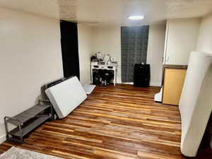 Misc room featuring a textured ceiling, baseboards, and wood finished floors