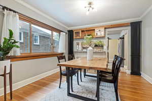 Dining space with baseboards, light wood finished floors, and crown molding