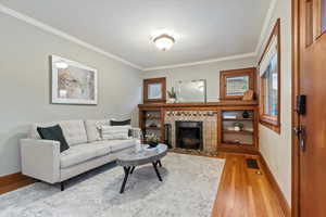 Living area featuring visible vents, ornamental molding, a fireplace, baseboards, and light wood-style flooring