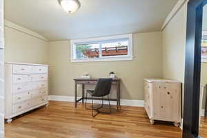 Home office with light wood-style floors, baseboards, and lofted ceiling