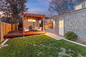 Back of property featuring a lawn, a pergola, a fenced backyard, and a deck