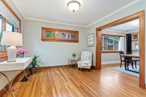 Living area featuring baseboards, ornamental molding, and wood finished floors