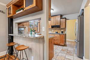 Kitchen with exhaust hood, freestanding refrigerator, a peninsula, baseboards, and tasteful backsplash