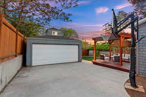 Garage at dusk featuring fence and a garage
