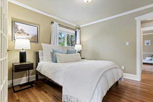 Bedroom with baseboards, ornamental molding, and wood finished floors