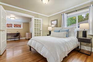Bedroom featuring crown molding, baseboards, french doors, and wood finished floors