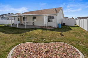 Rear view of property, shed, a fenced backyard and covered patio.