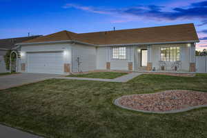 Single story home featuring a front lawn,  an attached garage, driveway, and a porch
