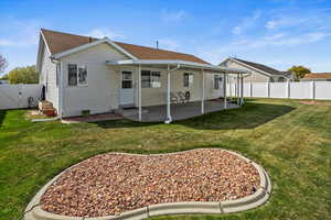 Back of house with a fenced backyard, a gate, a lawn, and a patio area