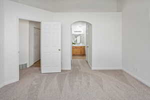 Primary bedroom with arched walkways, ensuite bathroom, planter shelf and new  carpet