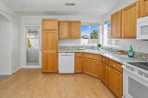 Kitchen featuring white appliances, plenty of natural light and light wood-style flooring