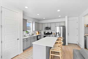 Kitchen featuring large island, upgraded cabinets and countertops, stainless steel appliances, gas range, and pantry.