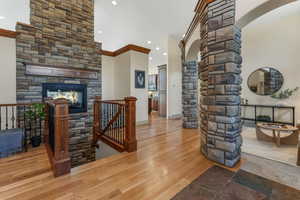 Interior space with crown molding, arched walkways, a stone fireplace, recessed lighting, and ornate columns