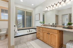 Bathroom featuring tile patterned flooring, a bath, toilet, and vanity