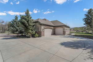 View of front of house featuring driveway, brick siding, an attached garage, a shingled roof, and stucco siding