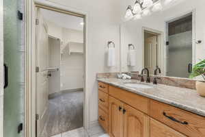 Full bath with vanity, a stall shower, tile patterned floors, and a spacious closet