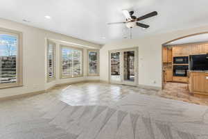 Unfurnished living room with ceiling fan, arched walkways, baseboards, light tile patterned floors, and visible vents