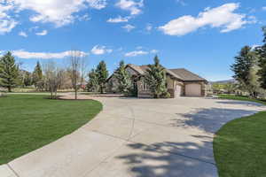 View of front facade featuring brick siding, driveway, a front lawn, and a garage