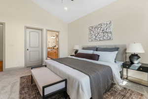 Bedroom with connected bathroom, high vaulted ceiling, baseboards, and carpet
