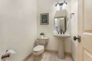 Half bath featuring toilet, baseboards, and tile patterned flooring
