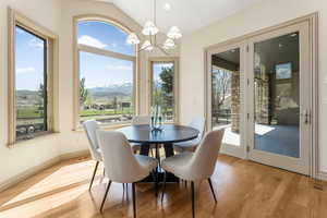 Dining room featuring an inviting chandelier, lofted ceiling, baseboards, a mountain view, and light wood-style flooring