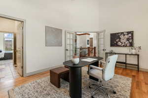 Home office featuring baseboards, a high ceiling, french doors, and light wood finished floors