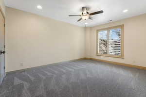 Carpeted empty room featuring baseboards, a ceiling fan, visible vents, and recessed lighting